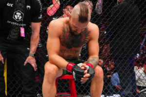 Conor McGregor sits in the octagon after his knee injury at UFC 329.
